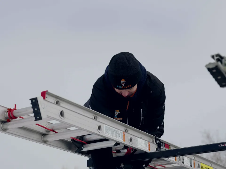 Winducks installer sliding the extension ladder back onto the truck rack at the end of a job