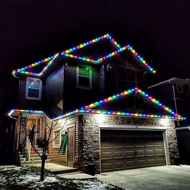Multicolour roofline Christmas lights on the peaks of a two-storey home
