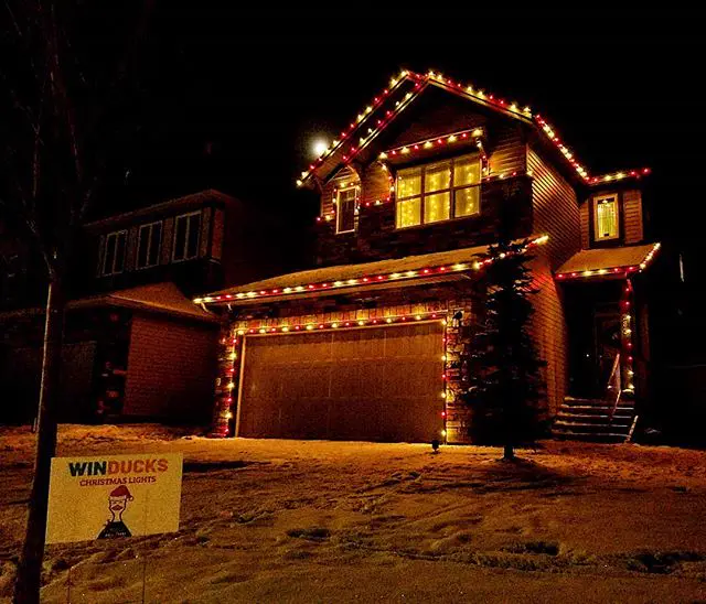 Multicolour roofline Christmas lights on a home with a Winducks yard sign